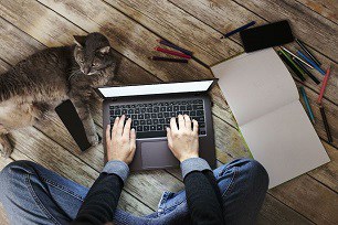 Man working on laptop with a cat trying not to be distracted